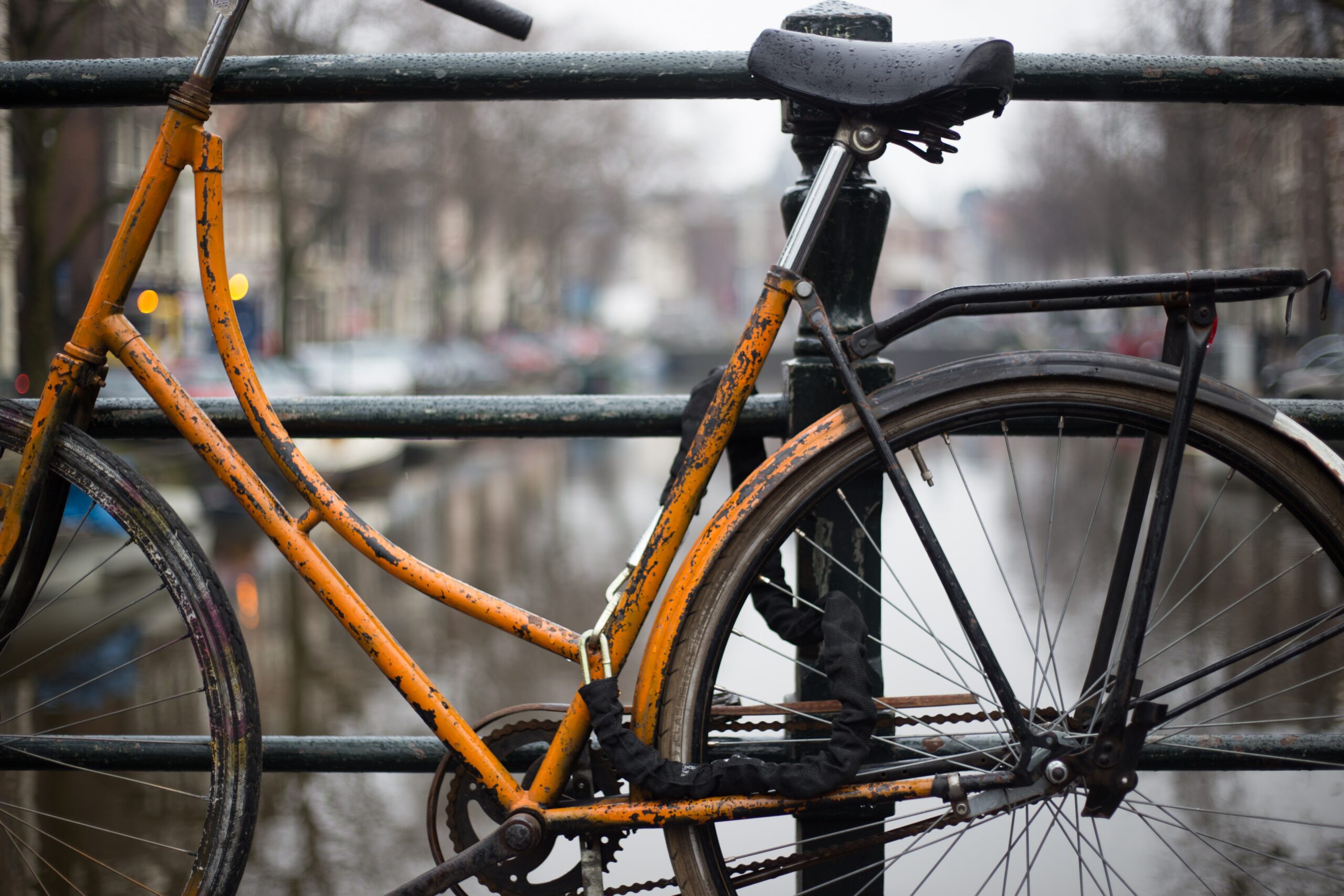 Rusty yellow bike chained to a railing