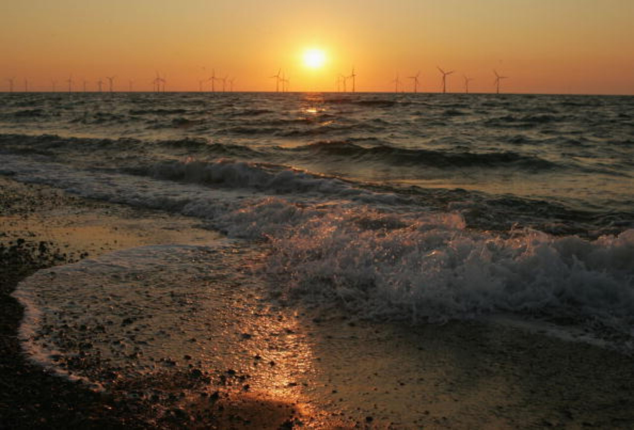 Offshore wind turbines on the horizon at sunset