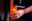 Hands holding a candle in a jar. The holder is wearing a black Greenpeace t-shirt.