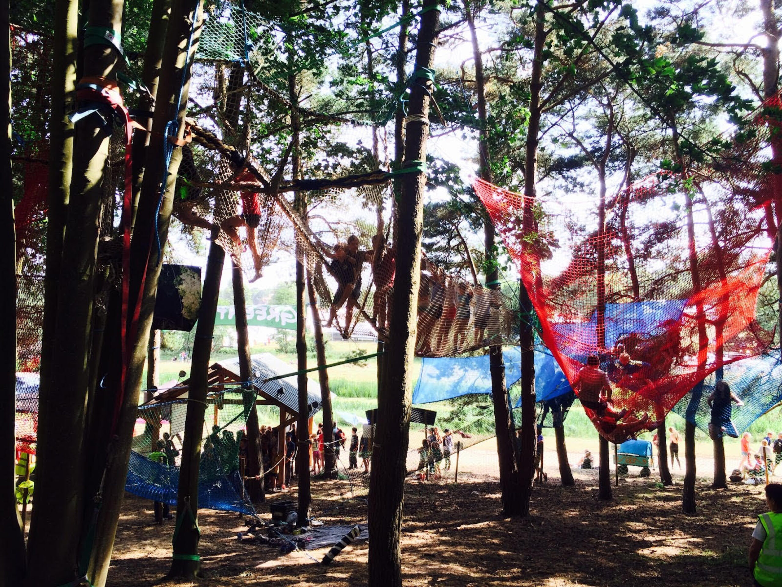 Children playing in large nets strung between tall trees