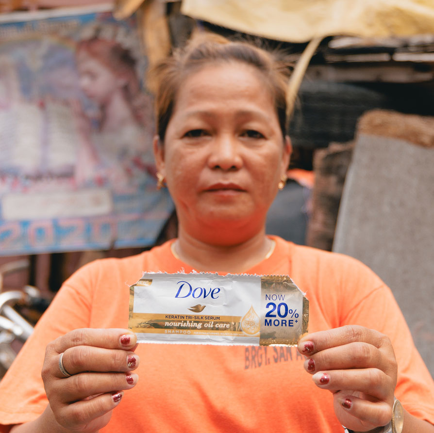 Street sweeper and waste worker Marilou Manangat holds up a Dove branded plastic sachet