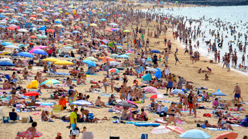 A crowded beach with lots of colourful umbrellas