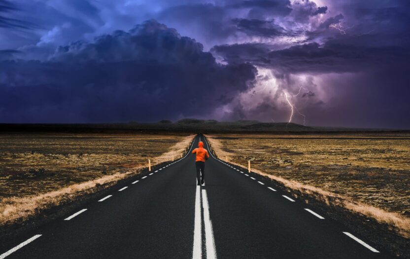 Photo montage of a lone runner on a straight road, with a dark, stormy sky ahead, representing eco-anxiety.