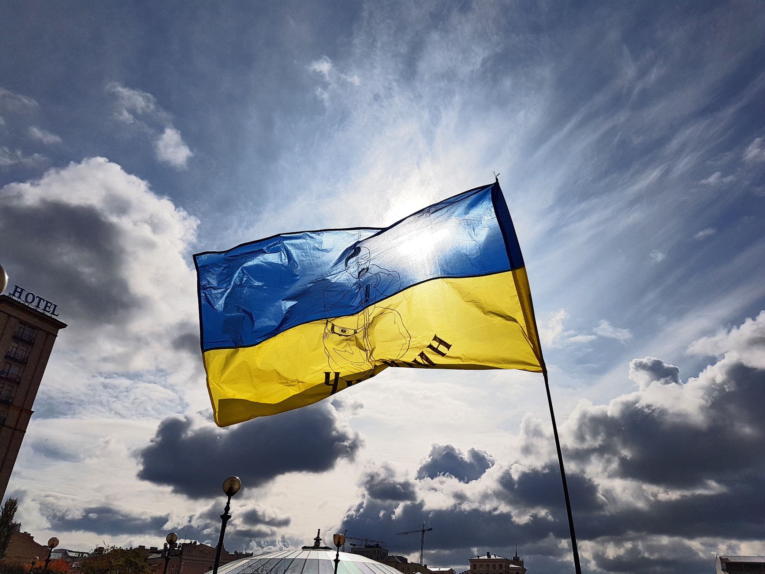 The Ukrainian blue-and-yellow flag, backlight by the sun against a blue sky with a few clouds