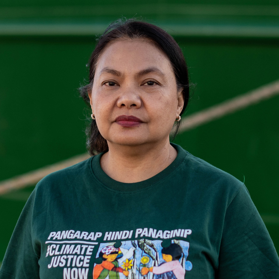 Virginia looks into the camera with a serious expression. She wears a tshirt with a climate justice slogan.
