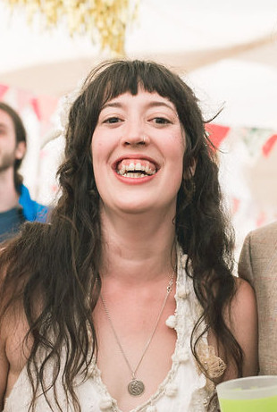 A portrait of a woman with long brown hair smiling brightly.