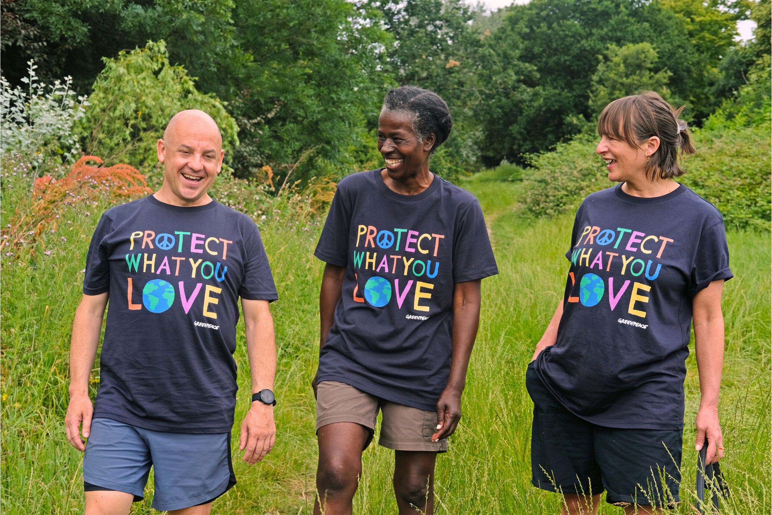 Three people walking through long grass with 'protect what you love' t-shirts on