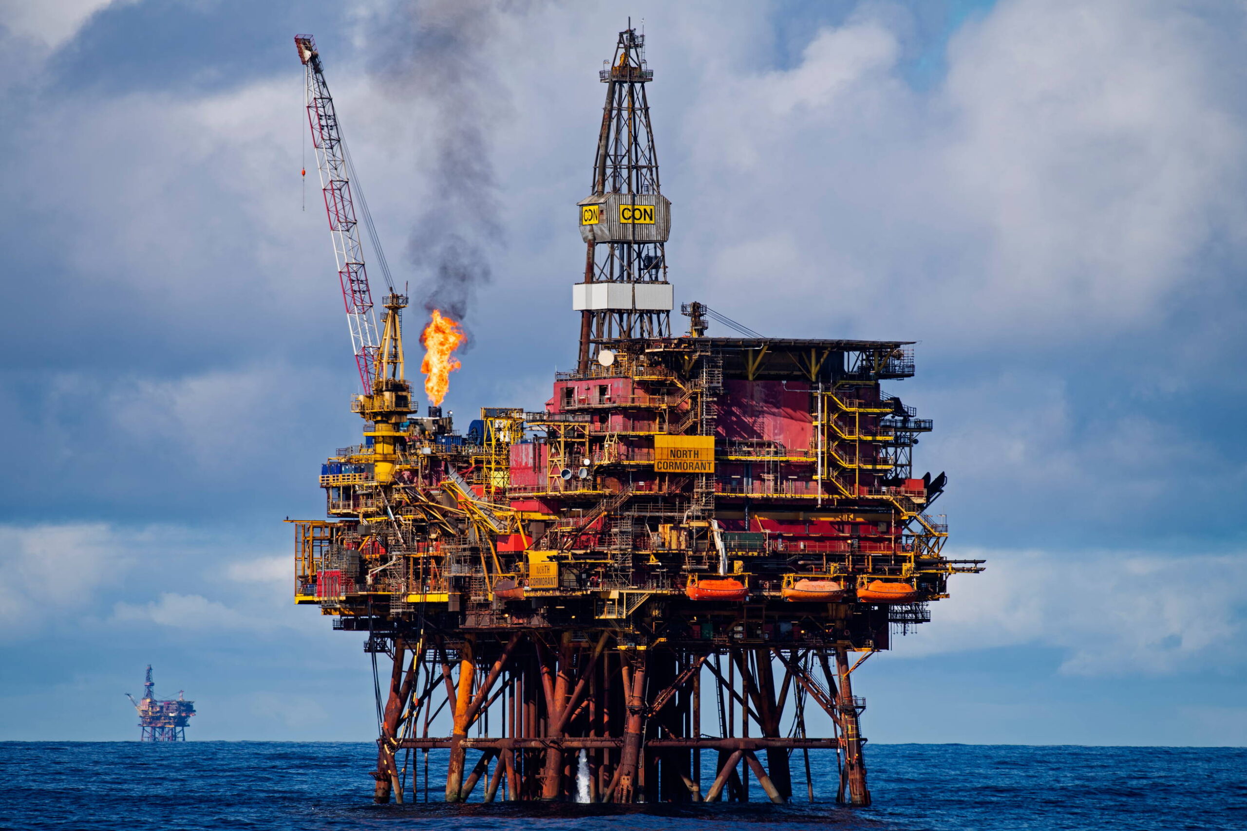 An oil rig at sea with another on the horizon