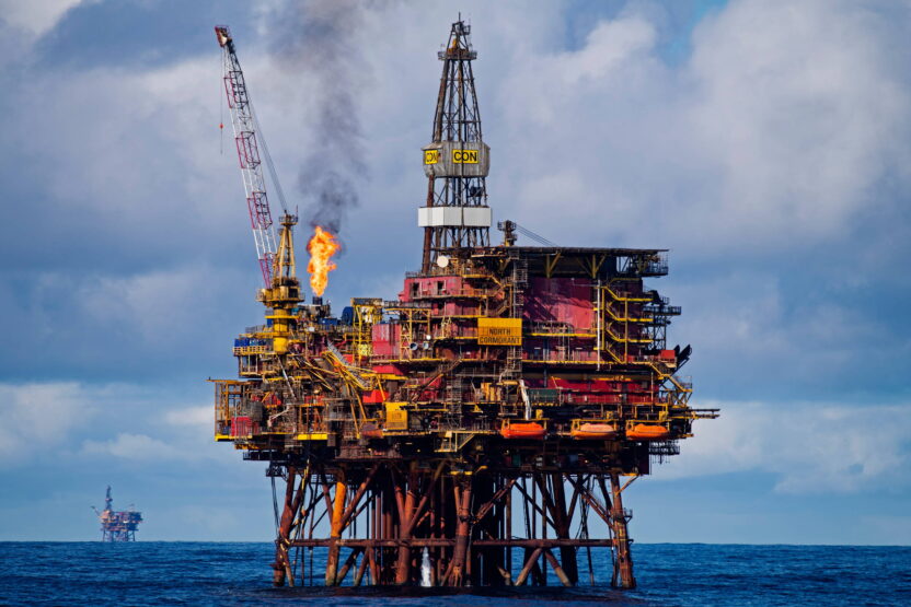An oil rig at sea with another on the horizon