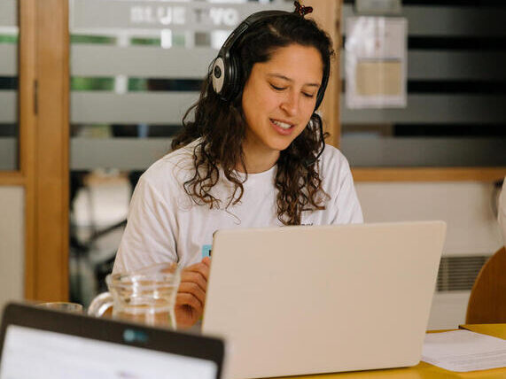 A woman with a headset and laptop takes part in a call