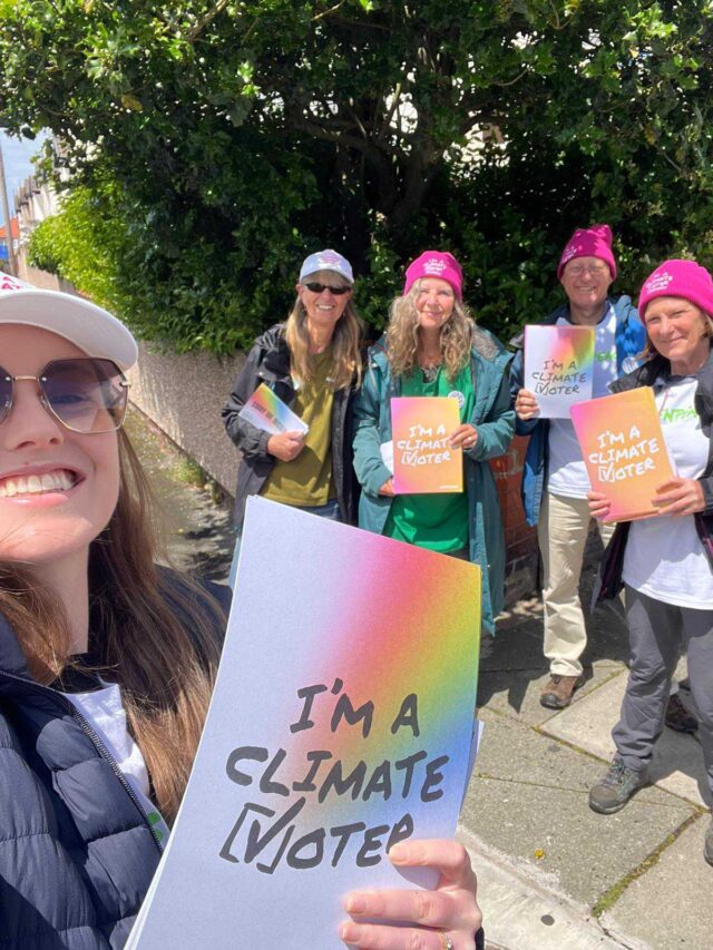 At the front of a march, a giant banner says 'we are climate voters'