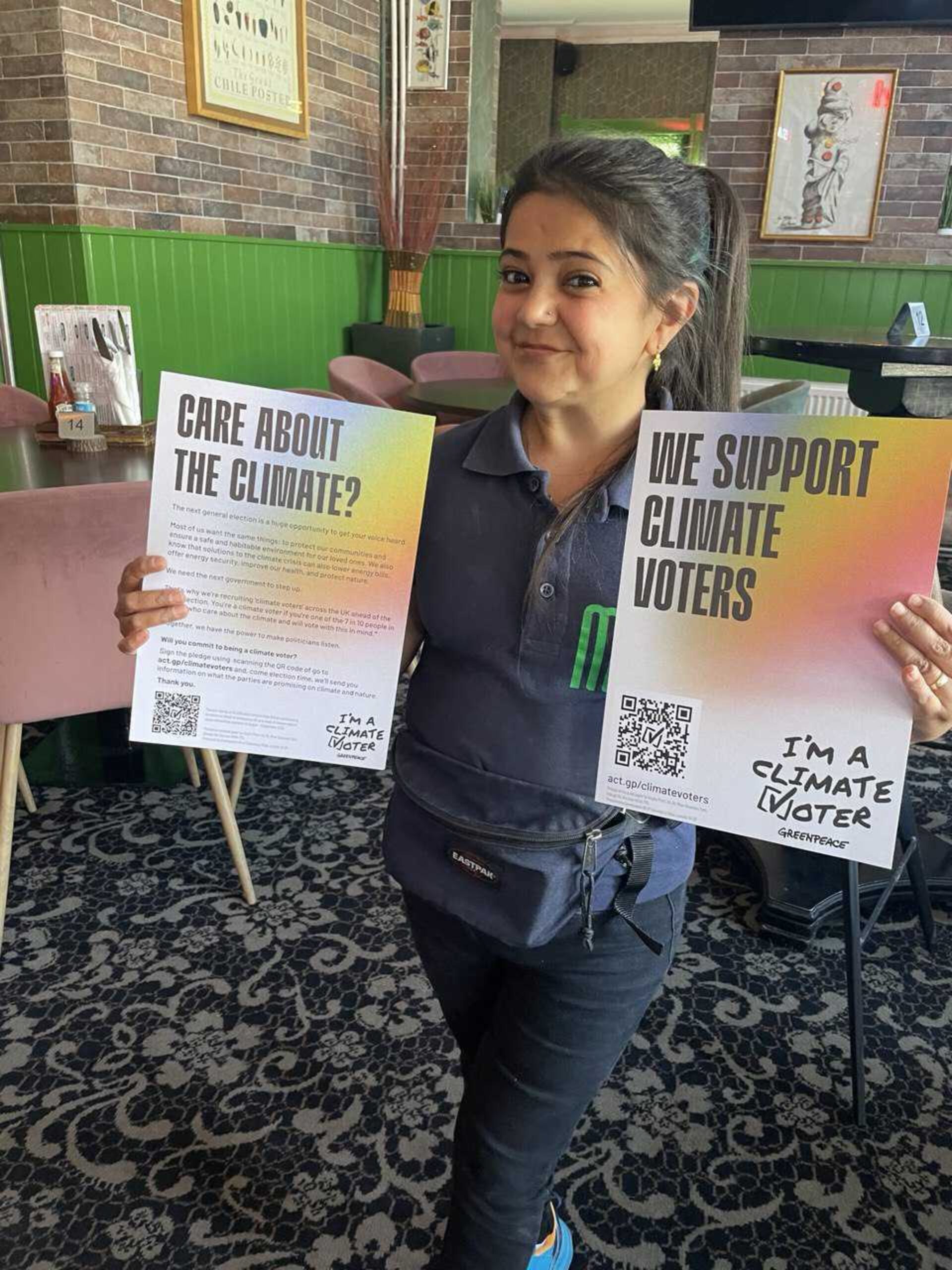 Person in a cafe holds up posters supporting Project Climate Vote