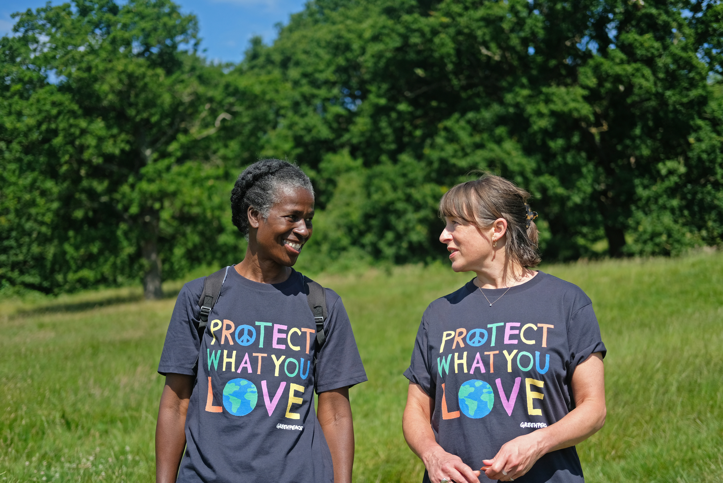 Two people walking through long grass with 'protect what you love' t-shirts on