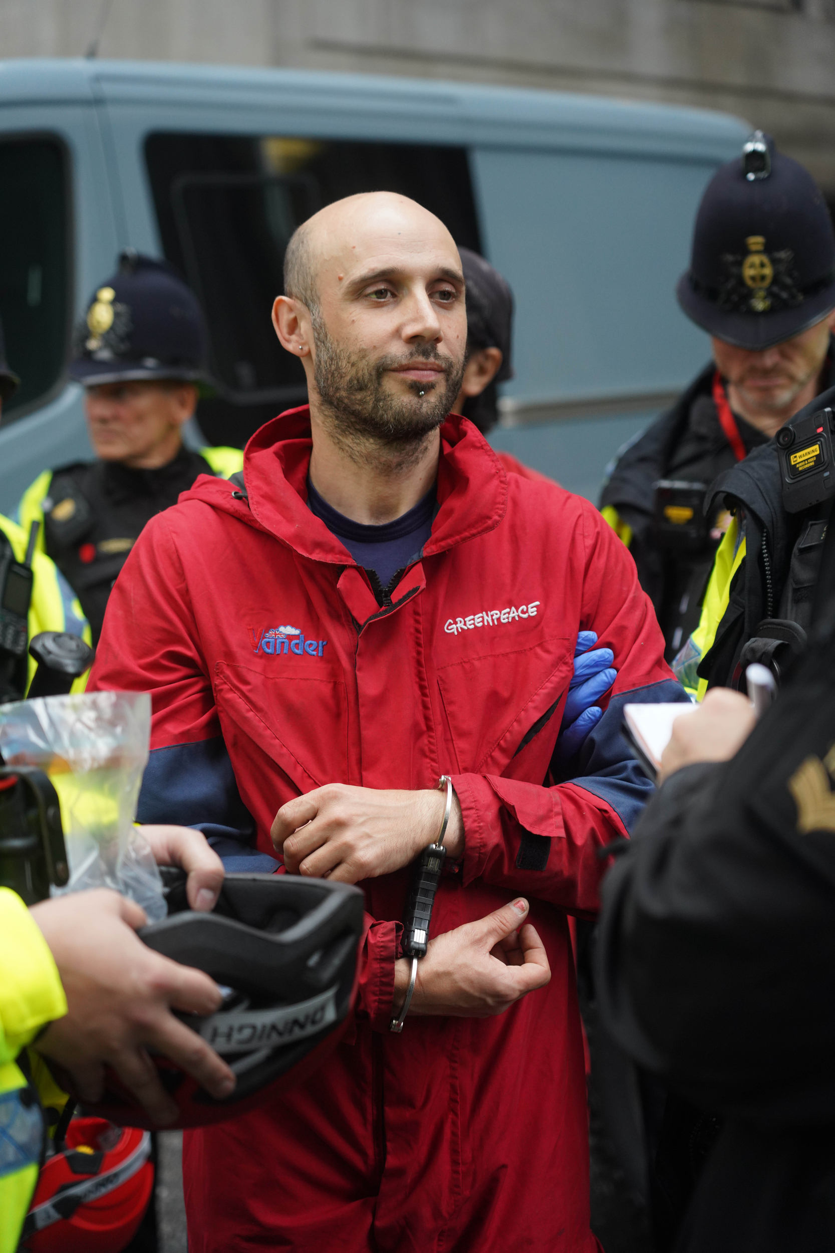 A calm-looking activist is handcuffed and led away by police.