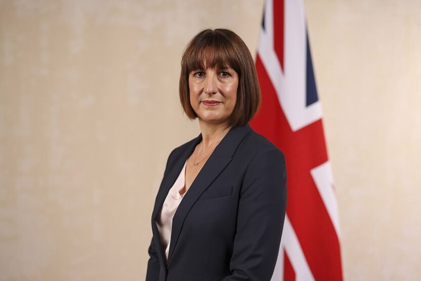 Chancellor of the Exchequer Rachel Reeves, standing in front of a flag