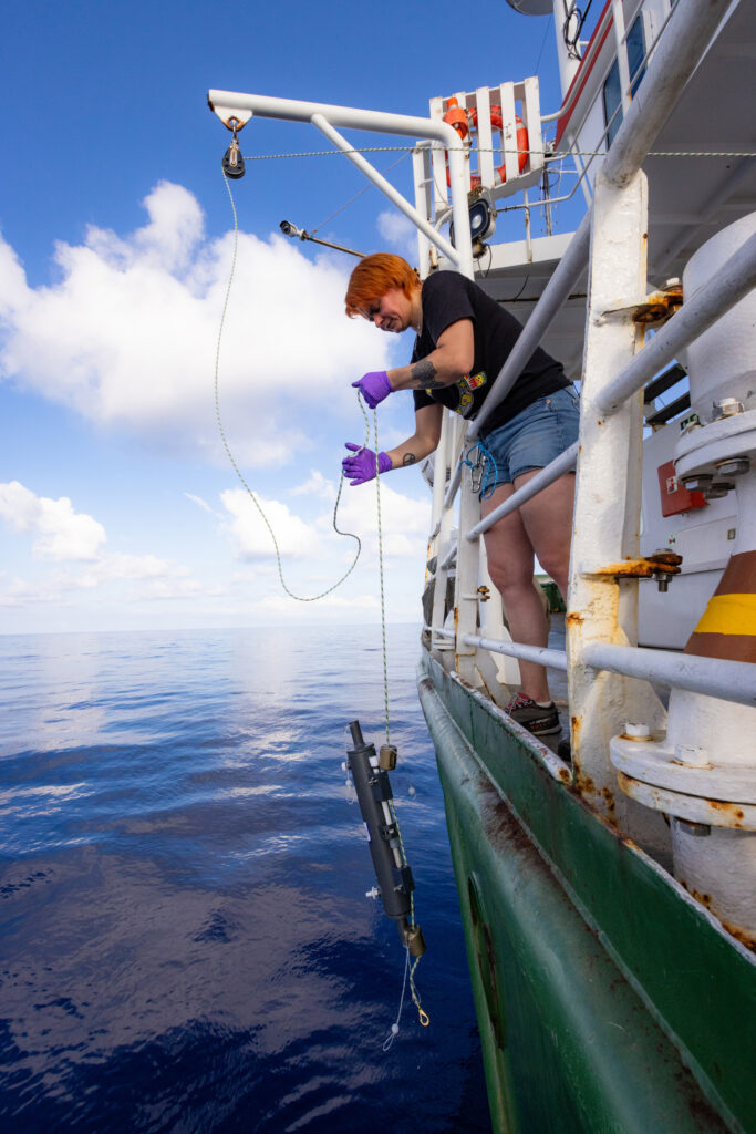 A Greenpeace campaigner lowers eDNA sampling equipment from the ship Arctic Sunrise into the water.