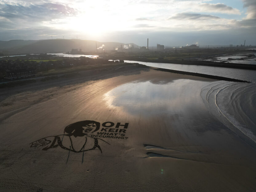 Atmospheric aerial shot of sand art showing the face of character Nessa from the TV series Gavin & Stacey with the sentence 'Oh Keir What's occurring?' next to the face.