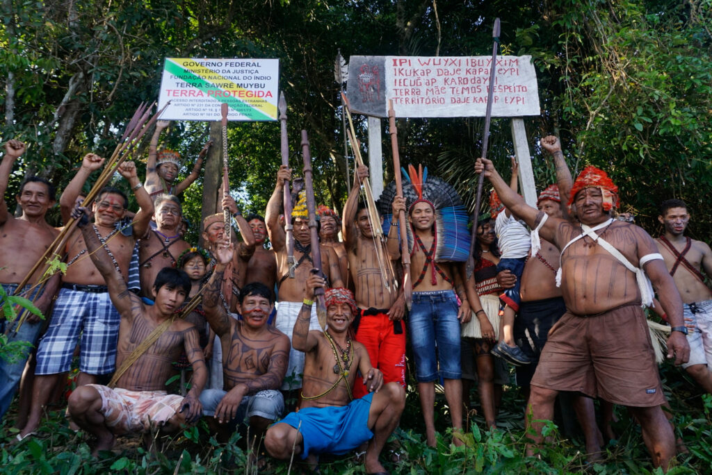 Group photo of Munduruku indigenous people with sign that says Terra Protegida in the background.