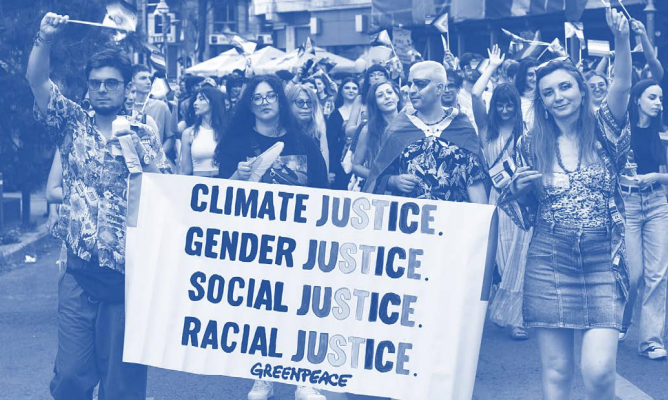 People on a march hold a banner that reads 'climate justice gender justice racial justice social justice'.