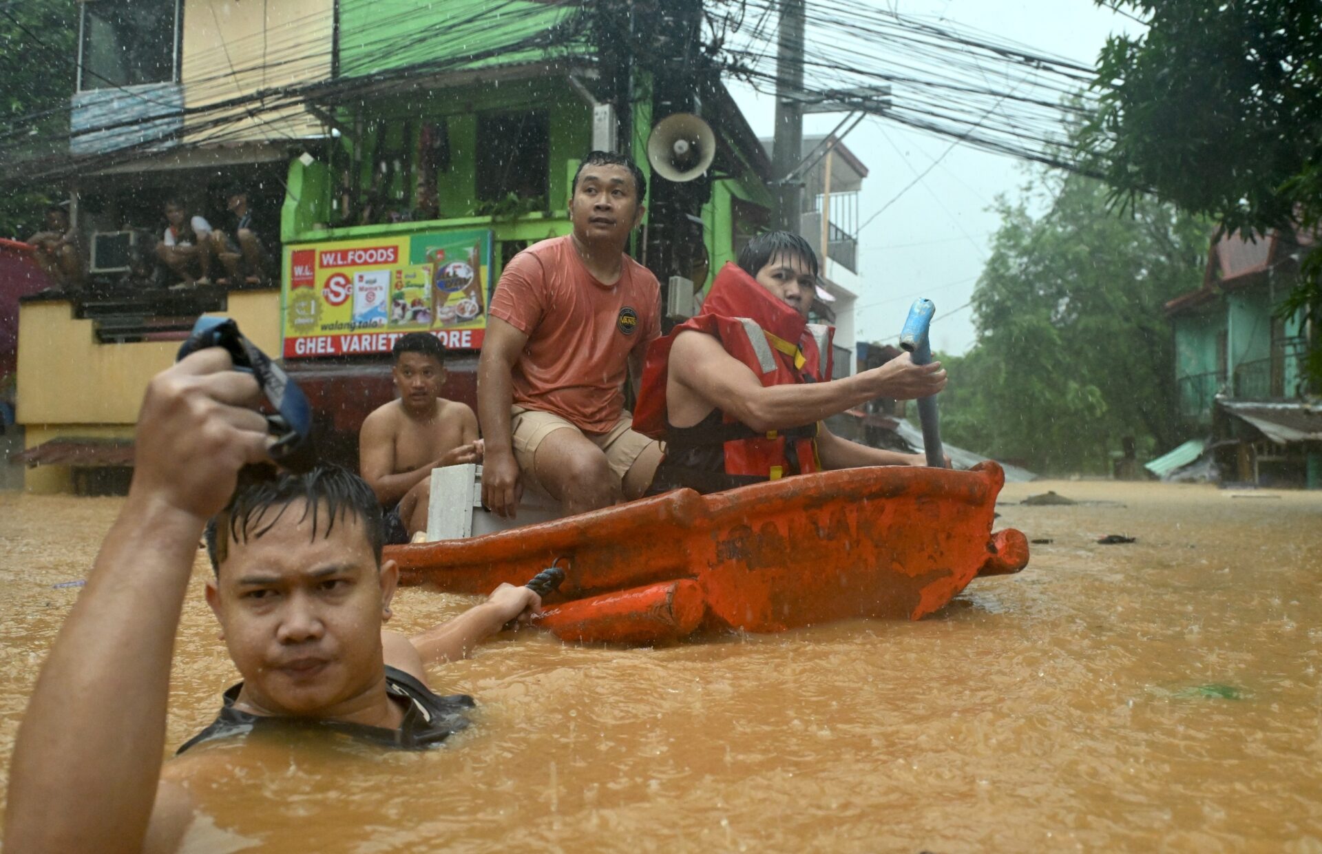Rescuer drags red boat with community members through high flood waters