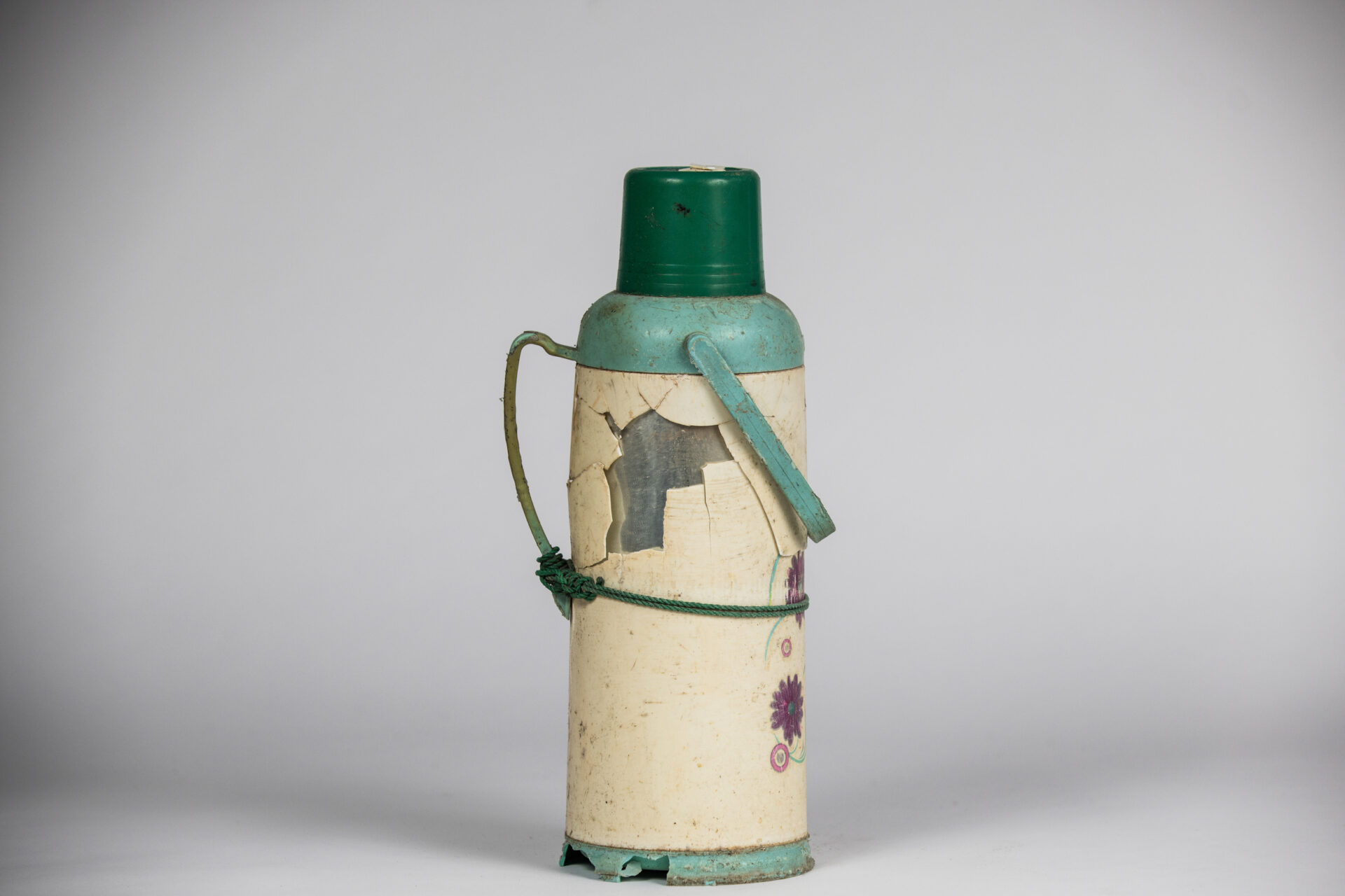 Broken Flask with green handle and lid photographed against white background