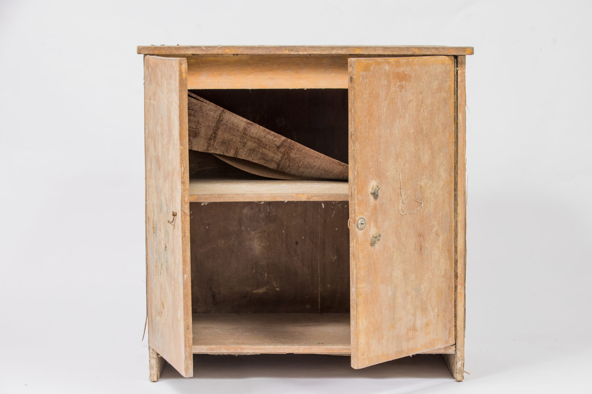 Light brown wooden cupboard photographed against a white background, damaged by flood waters