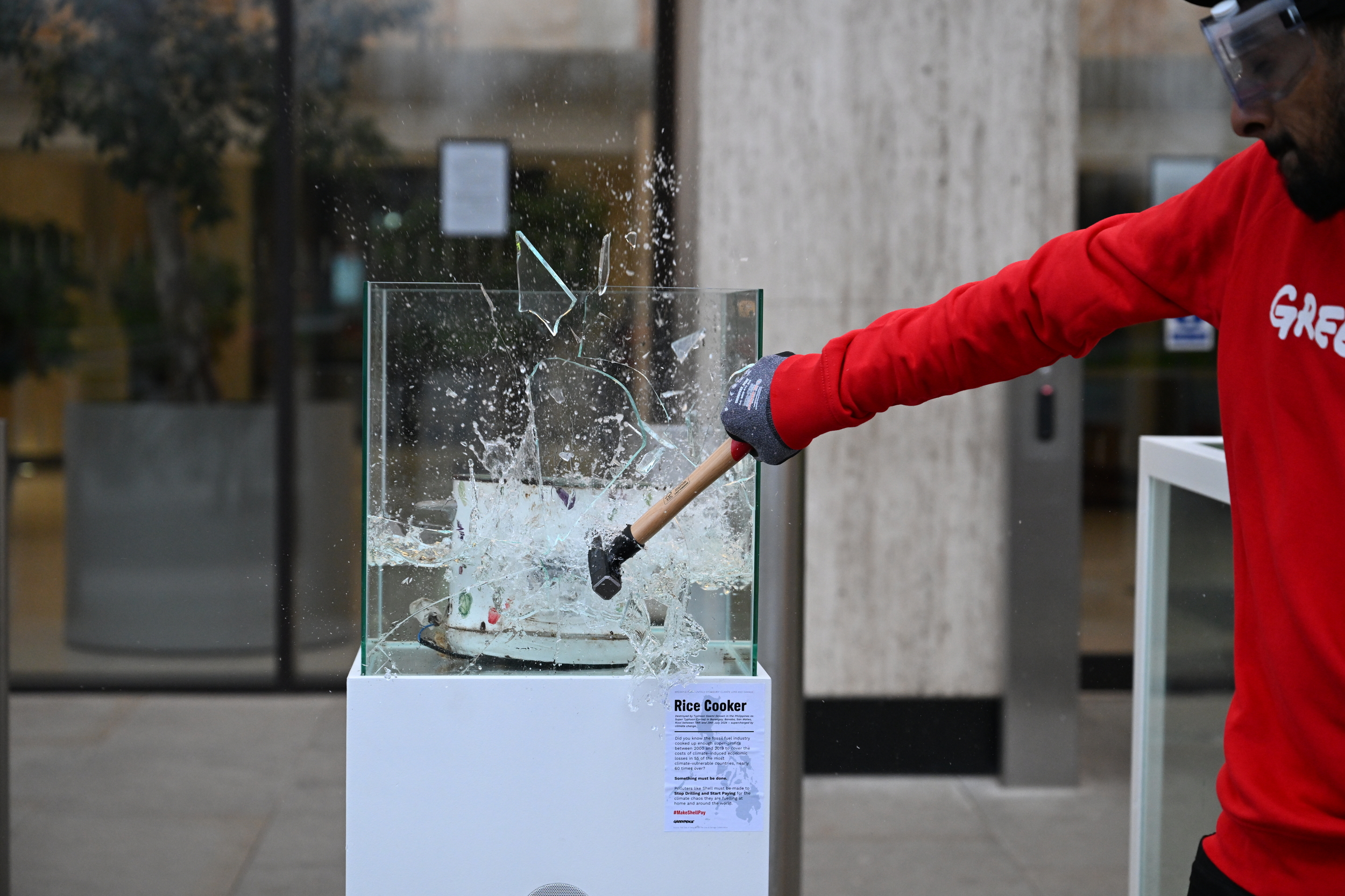 Activists smash water-filled display cases exhibiting typhoon-wrecked belongings at Shell’s HQ