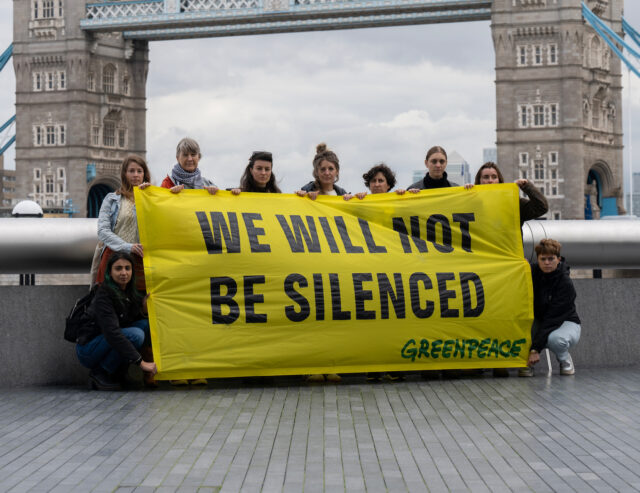 Activists stand in front of Tower Bridge with a banner saying we will not be silenced.