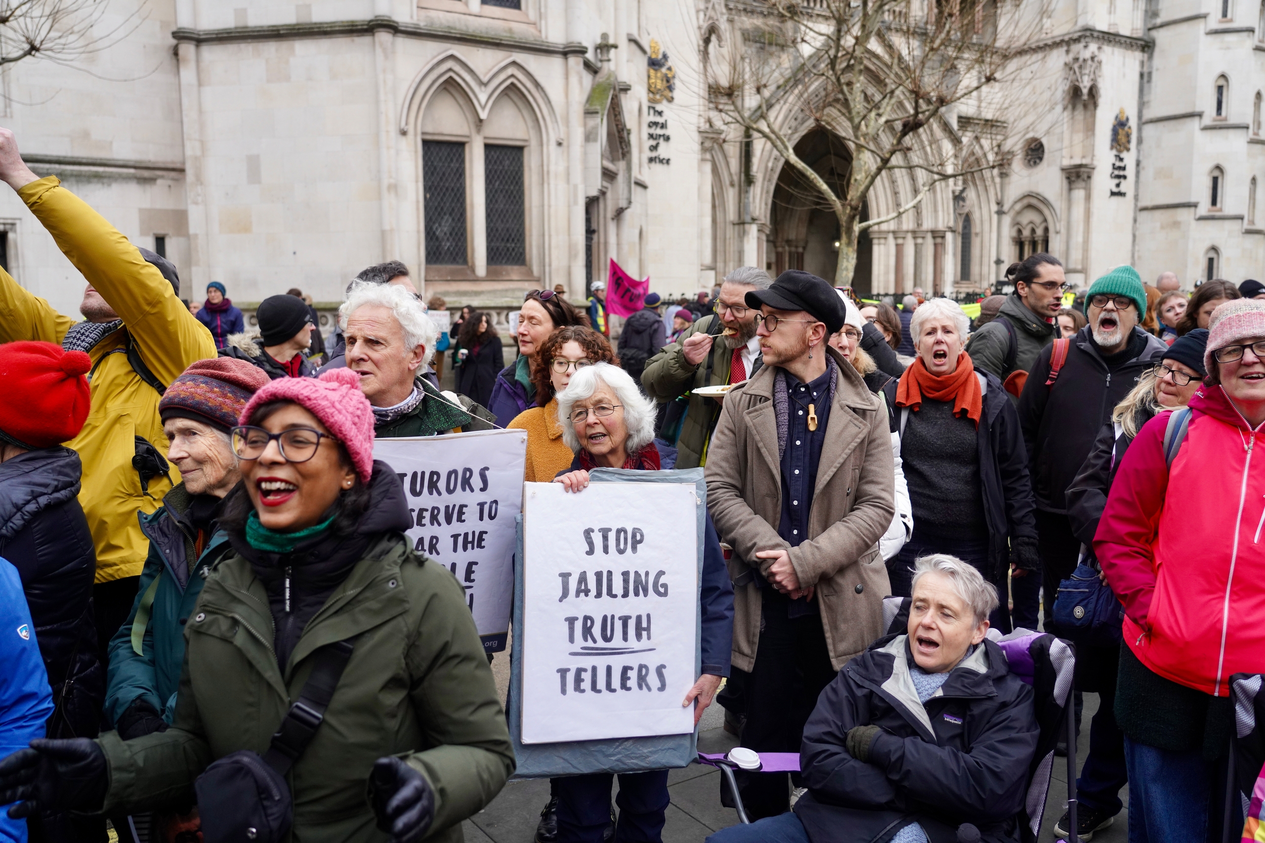 Protesters holding placards outside a court building in central London