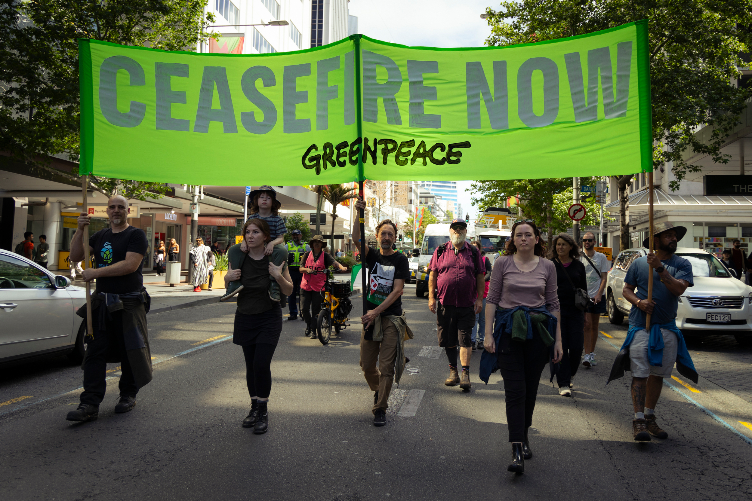 Activists march with a banner saying 'ceasefire now'.
