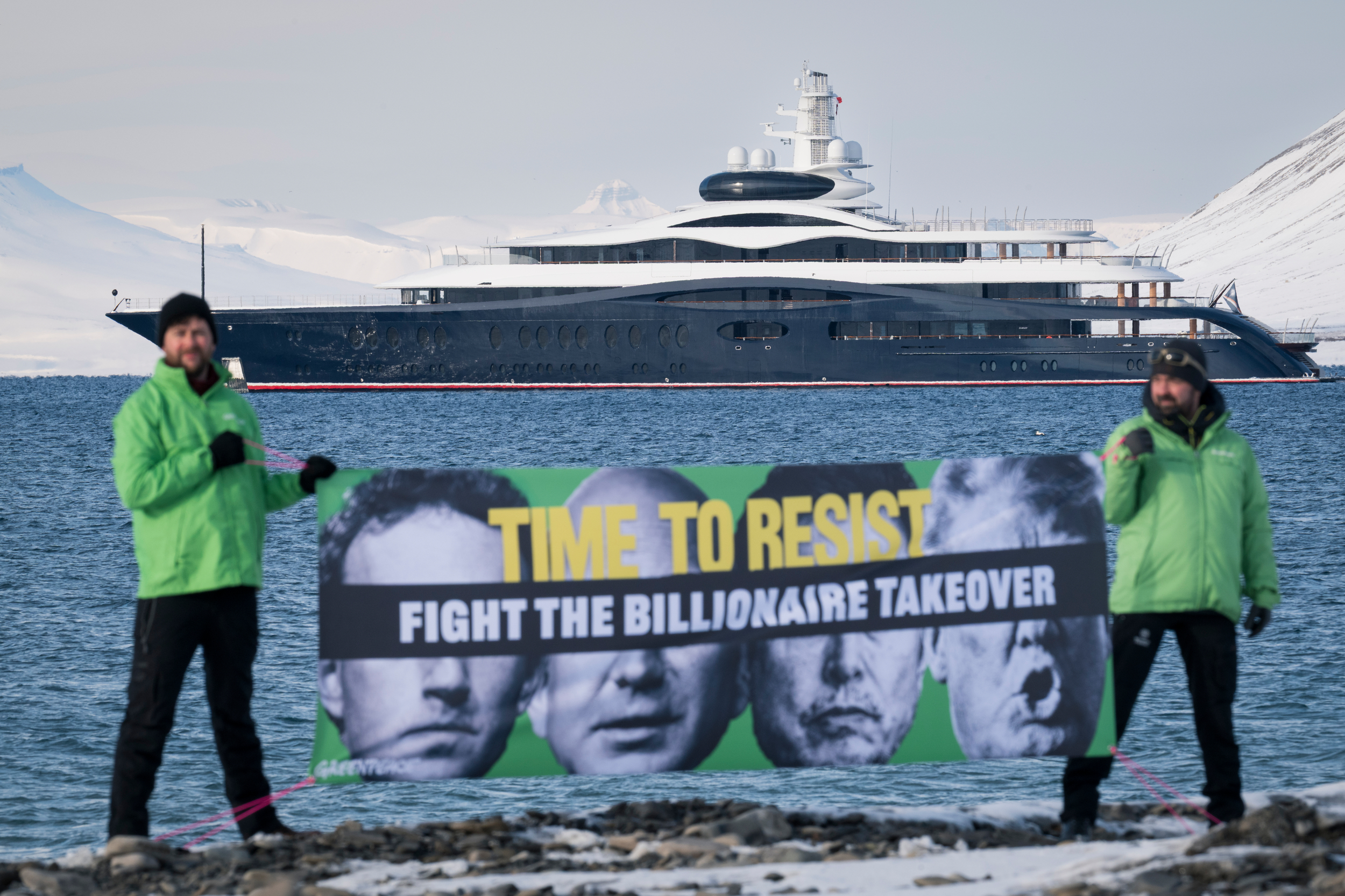 A climber unfurls an enormous yellow banner on a concrete surface