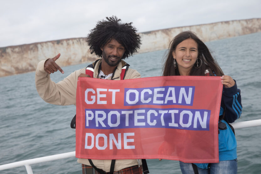 Mya-Rose Craig and Nadeem Perera hold a banner saying 'Get ocean protection done' onboard a Greenpeace boat