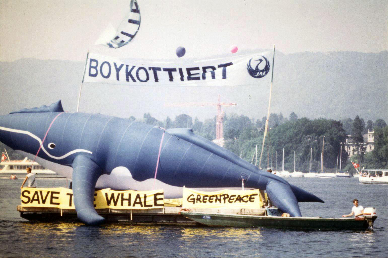 An inflatable is sitting on a boat. The banner reads 'Save the Whale'.