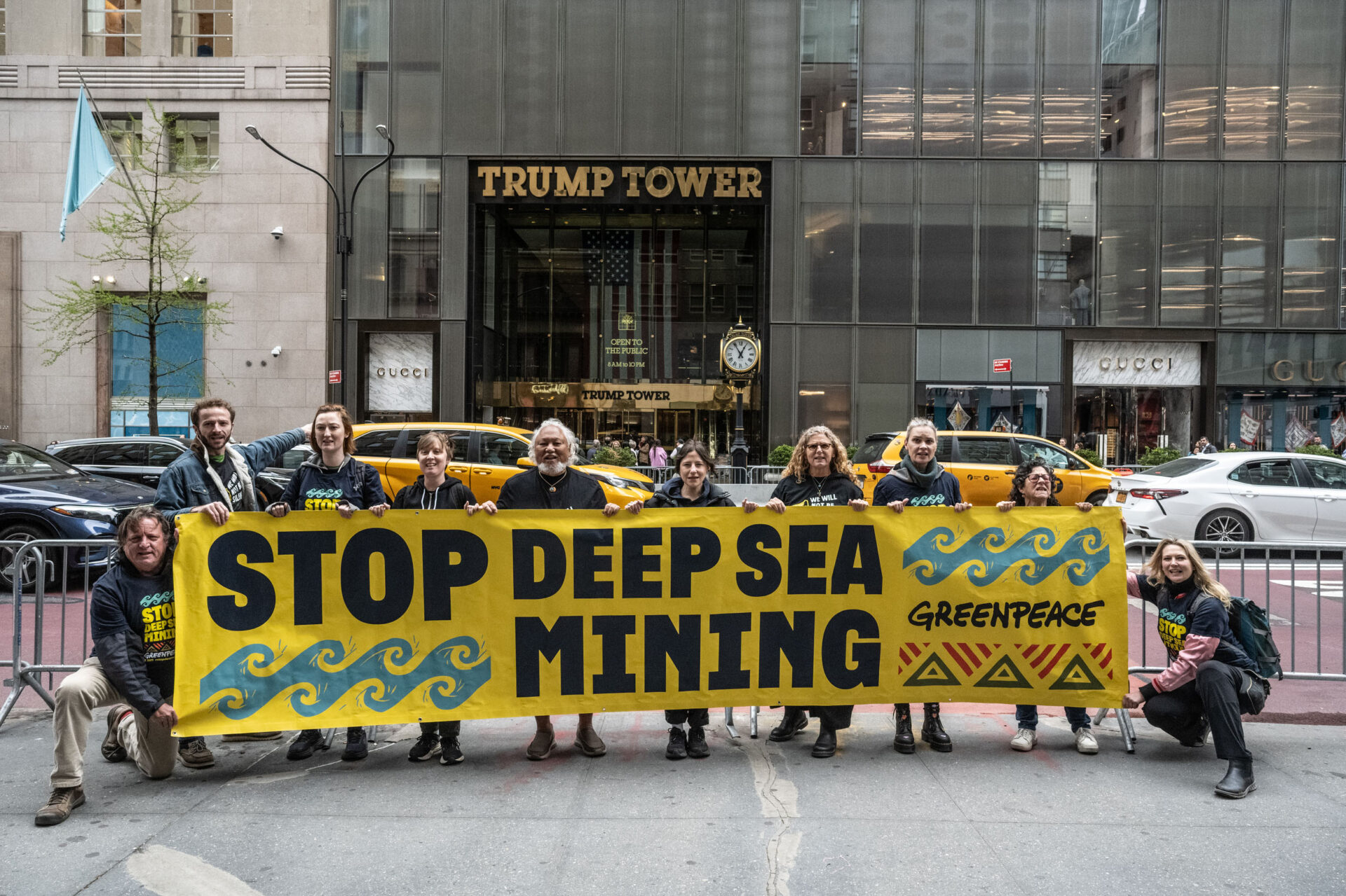A group of activists holds up a banner in front of Trump Tower. The banner reads 'Stop Deep Sea Mining'