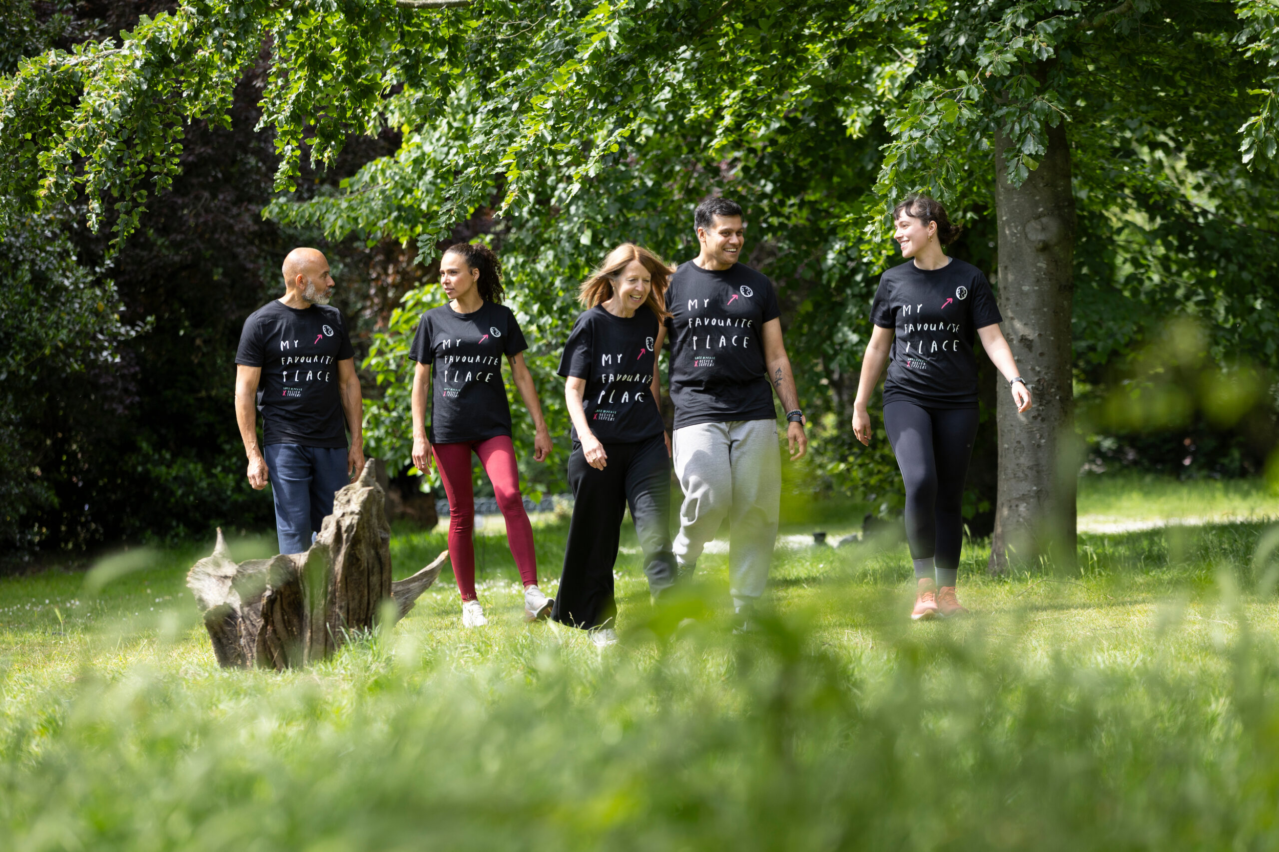 Five people walking in a lush green woodland.
