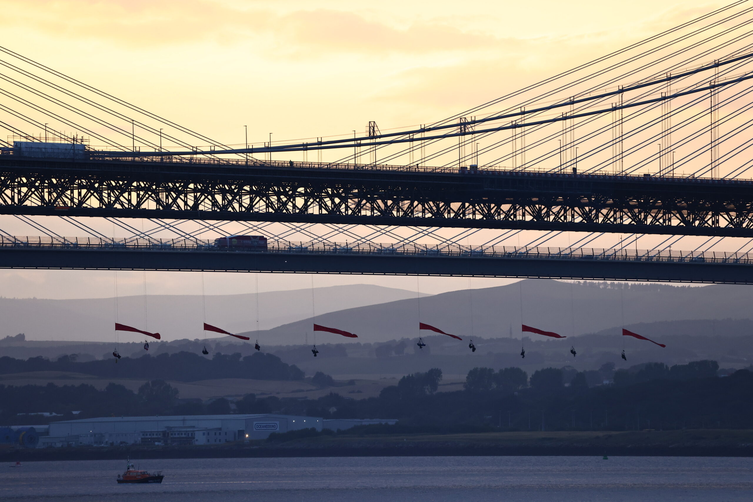 Greenpeace climbers abseil from Forth Road Bridge to block INEOS tanker in plastics protest.