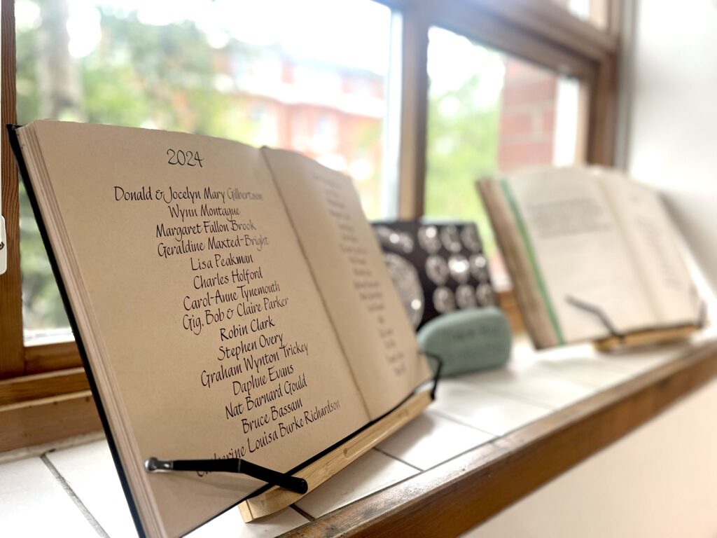 A book sits open on a stand on a window ledge in the Greenpeace office, with names written in beautiful calligraphy.
