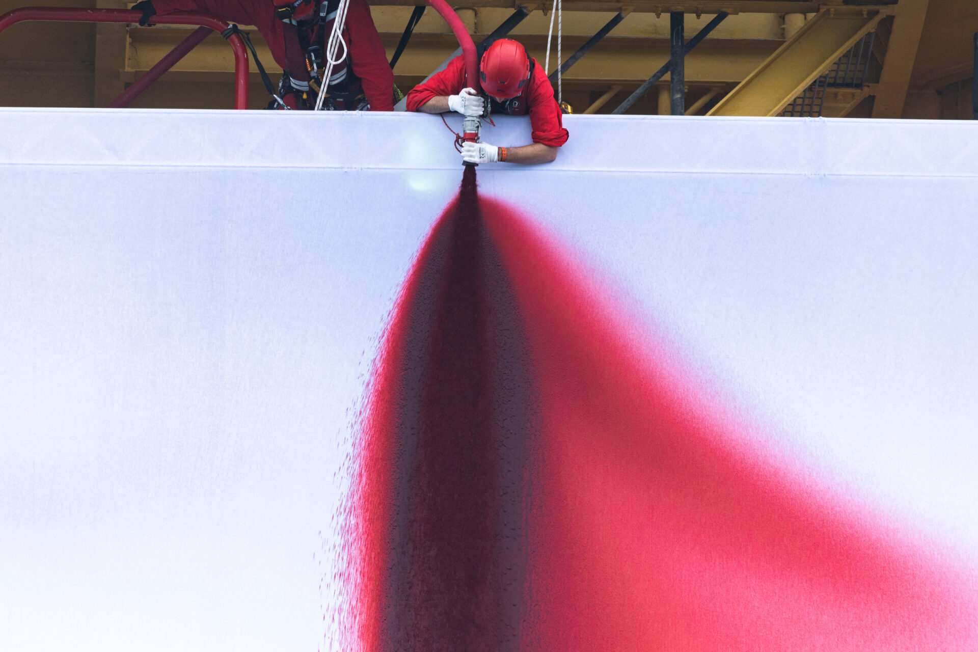 An activist directs a hose spraying fake blood onto a giant white fabric backdrop.