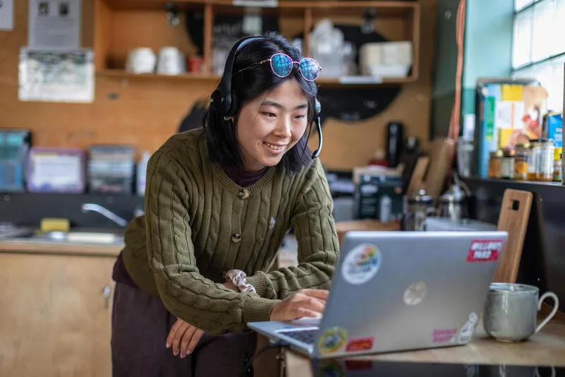 This photo shows a Greenpeace volunteer making calls to other supporters using her laptop. She wears a headset.